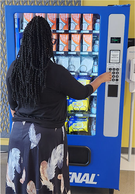 Woman purchasing a health care product from a vending machine