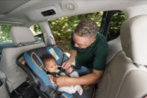 Infant being buckled in rear facing car seat by dad