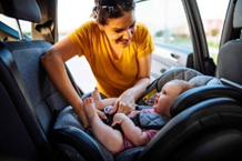 Infant being buckled in rear facing car seat by mom