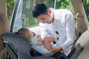 Dad buckling baby in car seat